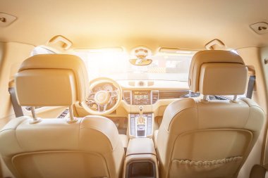 Araç içi lüks. Bej konforlu koltuklar, direksiyon, gösterge paneli, iklim kontrolü, hız göstergesi, ekran, ahşap süsleme ışığı