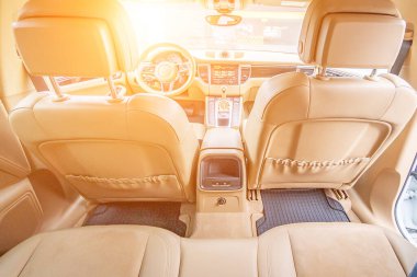 Araç içi lüks. Bej konforlu koltuklar, direksiyon, gösterge paneli, iklim kontrolü, hız göstergesi, ekran, ahşap süsleme ışığı