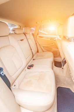 Araç içi lüks. Bej konforlu koltuklar, direksiyon, gösterge paneli, iklim kontrolü, hız göstergesi, ekran, ahşap süsleme ışığı