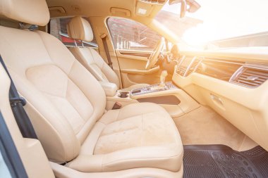 Araç içi lüks. Bej konforlu koltuklar, direksiyon, gösterge paneli, iklim kontrolü, hız göstergesi, ekran, ahşap süsleme ışığı