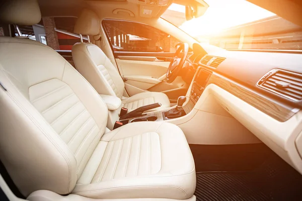 Araç içi lüks. Bej konforlu koltuklar, direksiyon, gösterge paneli, iklim kontrolü, hız göstergesi, ekran, ahşap süsleme ışığı