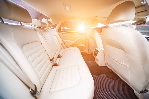 Araç içi lüks. Bej konforlu koltuklar, direksiyon, gösterge paneli, iklim kontrolü, hız göstergesi, ekran, ahşap süsleme ışığı