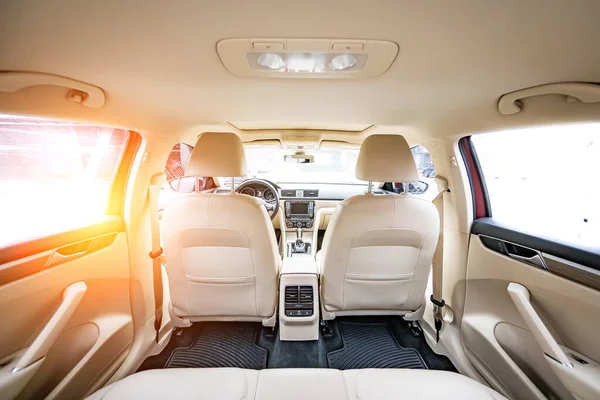 Araç içi lüks. Bej konforlu koltuklar, direksiyon, gösterge paneli, iklim kontrolü, hız göstergesi, ekran, ahşap süsleme ışığı
