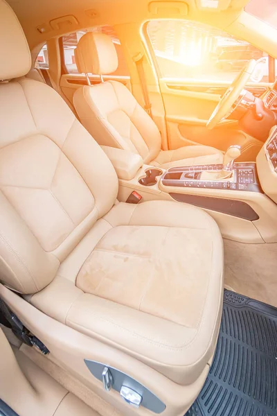 Araç içi lüks. Bej konforlu koltuklar, direksiyon, gösterge paneli, iklim kontrolü, hız göstergesi, ekran, ahşap süsleme ışığı