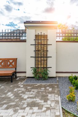 Arka ve ön bahçe kır evi bahçesi, çiçek açan bitki ve yeşil çimenler, kahverengi kaldırım ve turuncu tuğla duvar, arka planda her zaman yeşil ağaçlar, parktaki bakımlı peyzaj.