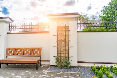 Arka ve ön bahçe kır evi bahçesi, çiçek açan bitki ve yeşil çimenler, kahverengi kaldırım ve turuncu tuğla duvar, arka planda her zaman yeşil ağaçlar, parktaki bakımlı peyzaj.