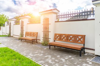 Arka ve ön bahçe kır evi bahçesi, çiçek açan bitki ve yeşil çimenler, kahverengi kaldırım ve turuncu tuğla duvar, arka planda her zaman yeşil ağaçlar, parktaki bakımlı peyzaj.