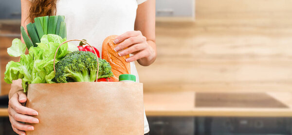 the woman takes out the groceries from the paper bag. concept of shopping and home delivery