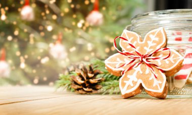 Tahta bir masanın üzerinde kar taneleri şeklinde zencefilli Noel ekmeği bir Noel ağacının arka planında