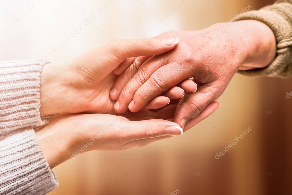 young hand holds hand of senior, care and help concept