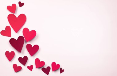 Pembe arka planda kalp şeklinde kırmızı sevgililer günü kartları.