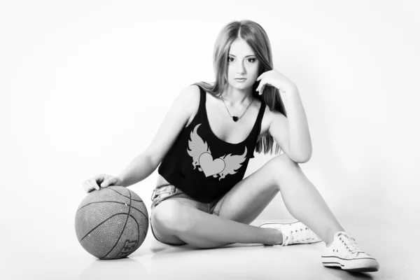 Young beautiful girl in shorts with the ball sits in the Studio on the white background — Stock Photo, Image