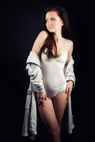 Beautiful young sexy girl brunette with makeup in the white bodysuit in the Studio on a black background — Stock Photo, Image