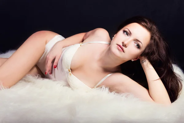 Красива молода сексуальна дівчина брюнетка з макіяжем у білому костюмі в студії на чорному тлі — стокове фото