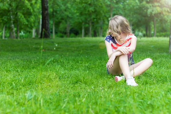 Young girl is smiling and happy sitting on the grass in summer Sunny day — Stock Photo, Image