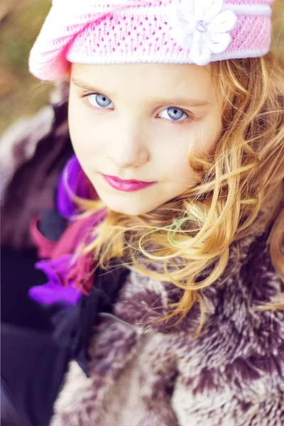 Little girl with blue eyes in the pink hat sitting in the forest — Stock Photo, Image