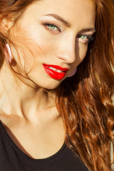 Beautiful sexy girl with red hair with big red lips with makeup in the city on a Sunny summer day — Stock Photo, Image