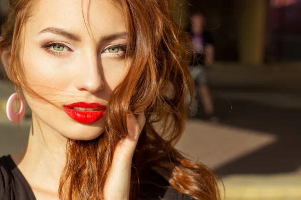 Beautiful sexy girl with red hair with big red lips with makeup in the city on a Sunny summer day — Stock Photo, Image