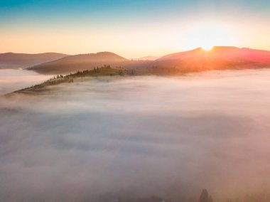 Sis şafakta dağların üzerine yayılır. Güneş ufuktan doğuyor. Sabah Ukraynalı Karpatlar. Hava aracı görünümü.