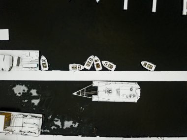 Rıhtımdaki karla kaplı tekneler suda. Hava aracı üst görünümü.