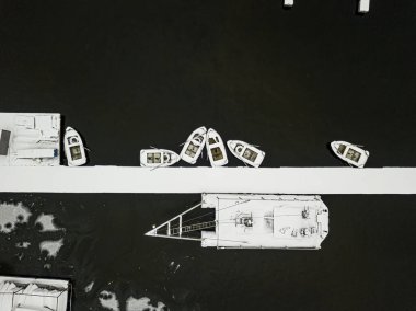 Rıhtımdaki karla kaplı tekneler suda. Hava aracı üst görünümü.
