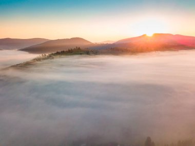 Sis şafakta dağların üzerine yayılır. Güneş ufuktan doğuyor. Sabah Ukraynalı Karpatlar. Hava aracı görünümü.