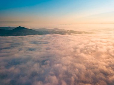 Dağlardaki sislerin üzerinden yüksek uçuş. Sabah Ukraynalı Karpatlar. Hava aracı görünümü.