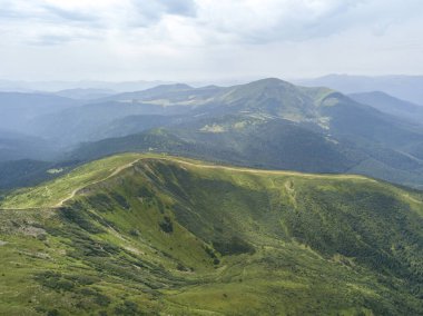Bulutlu havada Ukrayna Karpatlarının yüksek dağları. Hava aracı görünümü.