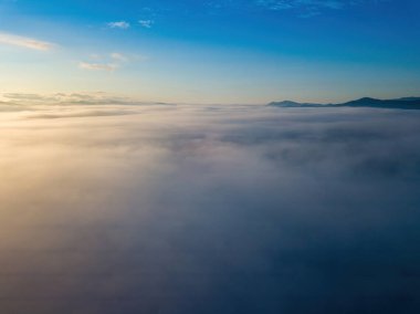 Ukrayna Karpatları 'nda sislerin üzerindeki şafak ışınları. Hava aracı görünümü.