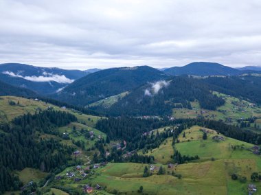 Yazın Ukrayna Karpat Dağları 'nın yeşil yamaçlarında. Bulutlu bir sabah, alçak bulutlar. Hava aracı görünümü.