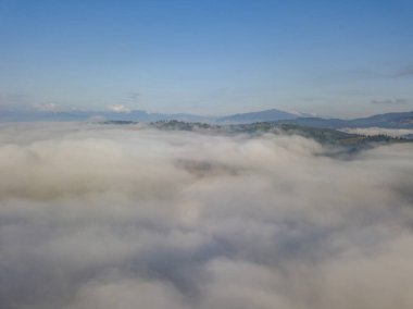Dağlardaki bulutların üstünde yüksek bir uçuş. Hava aracı görünümü.