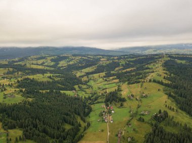 Yazın Ukrayna Karpat Dağları 'nın yeşil yamaçlarında. Bulutlu bir sabah, alçak bulutlar. Hava aracı görünümü.