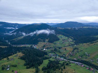 Yazın Ukrayna Karpat Dağları 'nın yeşil yamaçlarında. Bulutlu bir sabah, alçak bulutlar. Hava aracı görünümü.