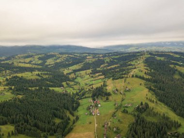 Yazın Ukrayna Karpat Dağları 'nın yeşil yamaçlarında. Bulutlu bir sabah, alçak bulutlar. Hava aracı görünümü.