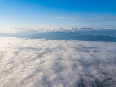 Dağlardaki bulutların üstünde yüksek bir uçuş. Hava aracı görünümü.