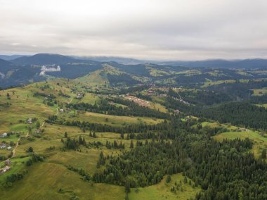 Yazın Ukrayna Karpat Dağları 'nın yeşil yamaçlarında. Bulutlu bir sabah, alçak bulutlar. Hava aracı görünümü.