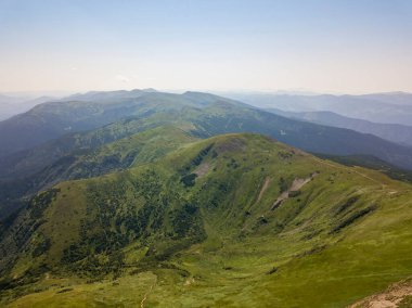 Bulutlu havada Ukrayna Karpatlarının yüksek dağları. Hava aracı görünümü.