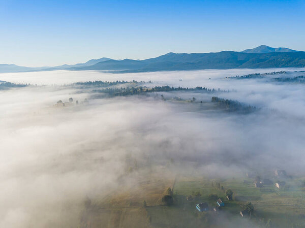 Летний полет над туманом в украинских Карпатах. Горы на горизонте. Толстый слой тумана покрывает горы сплошным ковром. Воздушный беспилотник.