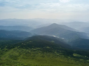 Bulutlu havada Ukrayna Karpatlarının yüksek dağları. Hava aracı görünümü.