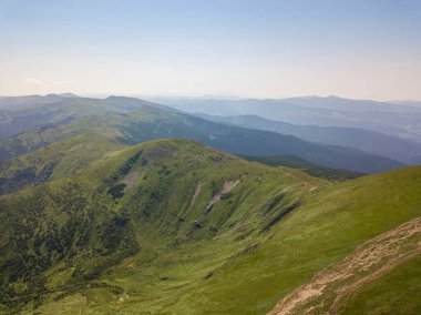 Bulutlu havada Ukrayna Karpatlarının yüksek dağları. Hava aracı görünümü.