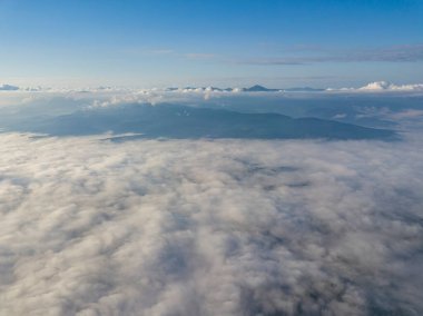 Dağlardaki bulutların üstünde yüksek bir uçuş. Hava aracı görünümü.