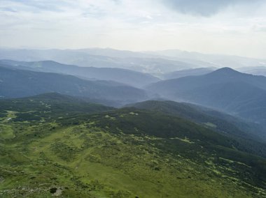 Bulutlu havada Ukrayna Karpatlarının yüksek dağları. Hava aracı görünümü.