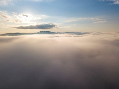 Ukrayna Karpatları 'nda yaz aylarında sislerin üzerinden uçarlar. Ufuktaki dağlar. Yoğun bir sis tabakası daimi bir halıyla dağları kaplar. Hava aracı görünümü.