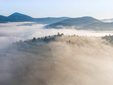 Ukrayna Karpatları 'nda yaz aylarında sislerin üzerinden uçarlar. Ufuktaki dağlar. Yoğun bir sis tabakası daimi bir halıyla dağları kaplar. Hava aracı görünümü.