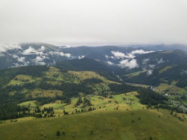 Yazın Ukrayna Karpat Dağları 'nın yeşil yamaçlarında. Bulutlu bir sabah, alçak bulutlar. Hava aracı görünümü.