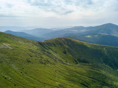 Bulutlu havada Ukrayna Karpatlarının yüksek dağları. Hava aracı görünümü.