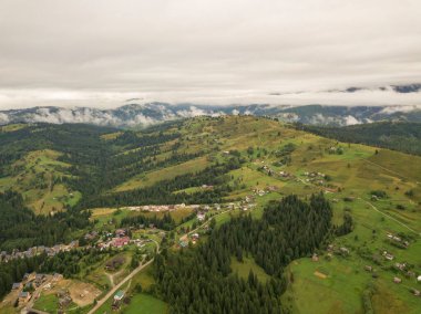 Yazın Ukrayna Karpat Dağları 'nın yeşil yamaçlarında. Bulutlu bir sabah, alçak bulutlar. Hava aracı görünümü.