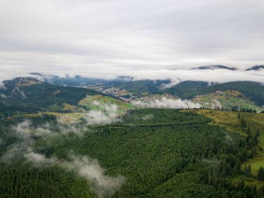 Yazın Ukrayna Karpat Dağları 'nın yeşil yamaçlarında. Bulutlu bir sabah, alçak bulutlar. Hava aracı görünümü.