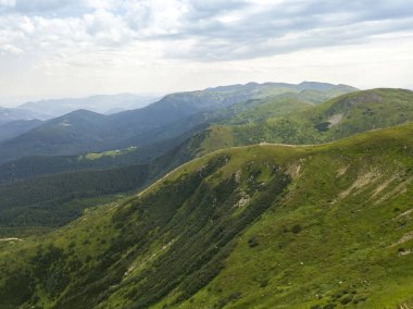 Bulutlu havada Ukrayna Karpatlarının yüksek dağları. Hava aracı görünümü.