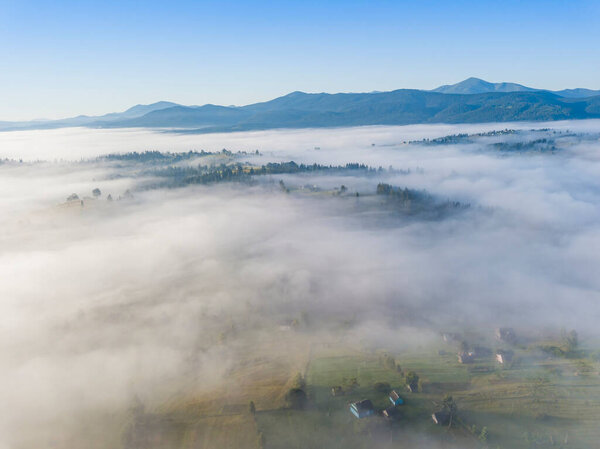 Летний полет над туманом в украинских Карпатах. Горы на горизонте. Толстый слой тумана покрывает горы сплошным ковром. Воздушный беспилотник.